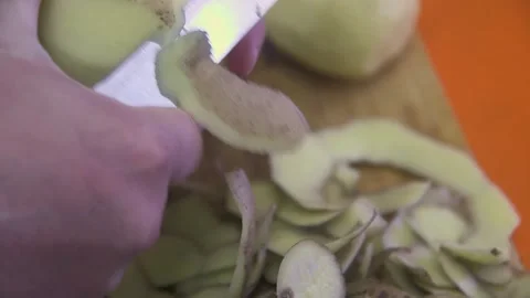 The hands of the cook are peeling a large potato with a knife, for cooking f Vídeos de archivo 223347537