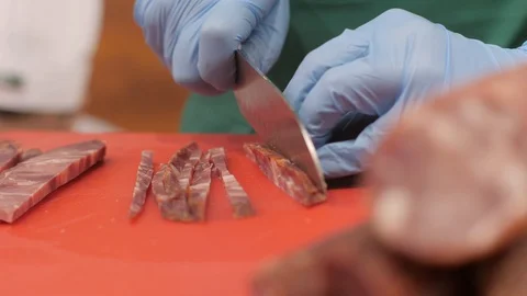 Hands of cook cutting jerky meat on slices for cooking in restaurant kitchen Video stock 90910926