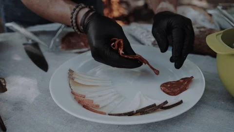 Hands of the cook in gloves put sausage and meat products on a plate with cheese Stock Footage 99301130