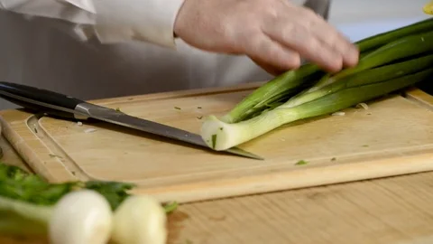 Hands of the cook knife big kitchen a fresh green feather onions on a chopping Stock Footage 79311642