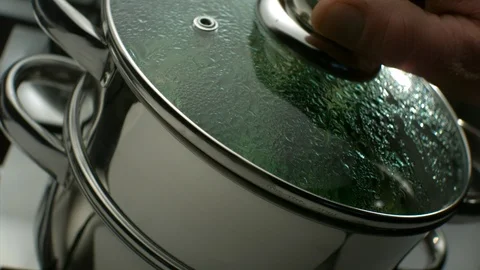 Hands of a cook opens the lid of a double boiler and shows green broccoli Stock Footage 113605059