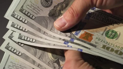 Hands Counting cash a stack of 100 dollar bills against a dark backdrop Video stock 314382322