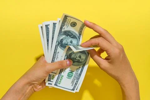 Hands counting hundred dollar bills on yellow background Stock Photos