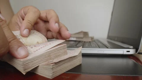 Hands counting a lot of thousands Thai baht banknotes money near laptop. Stock Footage 238503674