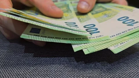 Hands counting multiple 100 euro banknotes on dark surface Stock Footage 310851546