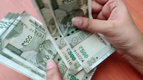 Hands counting new Rs 500 Rupees Indian Currency notes against a wooden bokeh Stock Footage 133713161