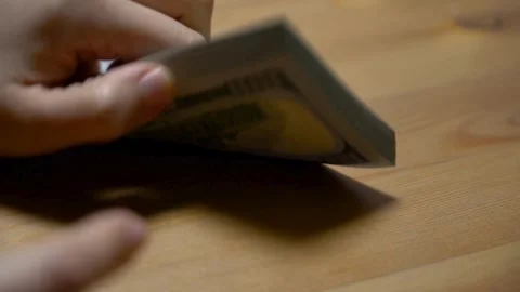 Hands counting out hundred dollar onto the table. Person calculates wages, .. Stock Footage 266474358