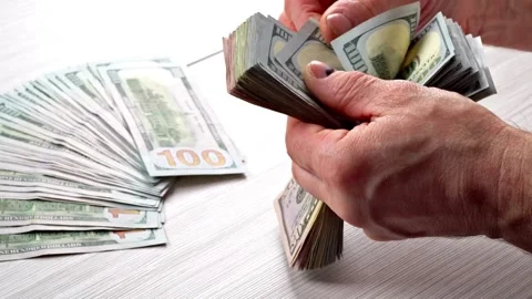 Hands counting out hundred dollar onto the table. Person calculates wages, .. Stock Footage 266474800