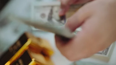 Hands counting stack of one hundred dollar bills with gold bars in backgrou.. Stock Footage 337448108