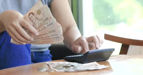 Hands counting Thai banknotes while using a calculator, budgeting, personal.. Stock Footage 339880916