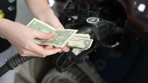 Hands counts crumpled dollar bills against the background of fueling car 库存影片 132137999