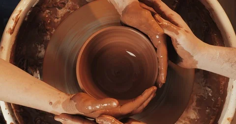 Hands of couple form a pot of clay on a potter's wheel. A male hand helps a Stock Footage 106496872