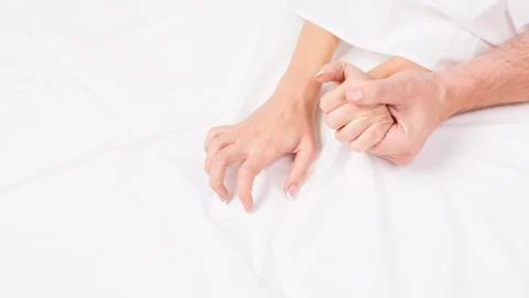 Hands of couple pulling white sheets in lust and orgasm. Stock Photos