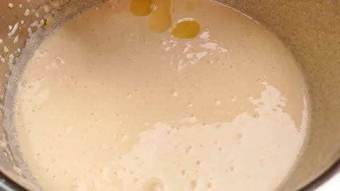 Hands cracking an egg into a bowl with batter preparing for making brownie cakes Stock Footage 158659711