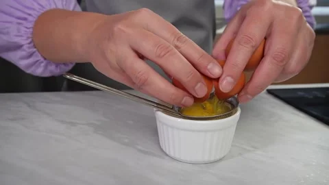Hands cracking egg into strainer over bowl in kitchen setting , step 2. 스톡 동영상 292007811