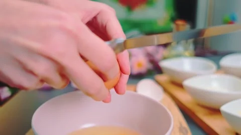 Hands cracking eggs into a pink mixing bowl in kitchen Stock Footage 342861872