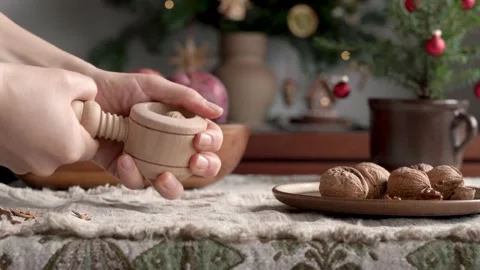 Hands cracking walnuts with a nutcracker, with a decorated Christmas tree Video stock 167976602