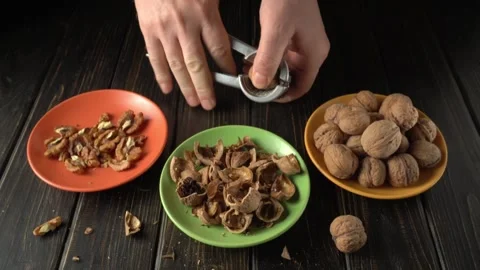 Hands cracking walnuts with a nutcracker, revealing the nut inside while Vídeos de archivo 327916173