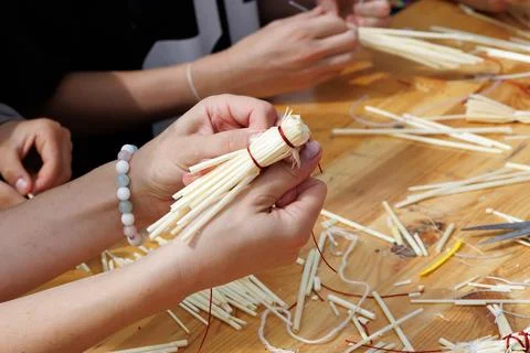 Hands craft a bundle of thin, pale bamboo sticks. Thread wraps the sticks t.. Stock Photos