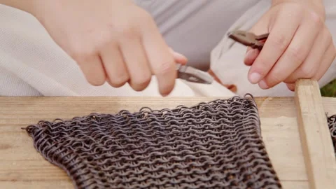 Hands Crafting Chainmail Armor with Pliers and Metal Rings, Close-Up Stock Footage 322089450