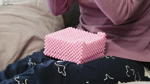 Hands crafting pink beaded box with fine needlework on dark patterned fabri.. Stock Footage 334570351