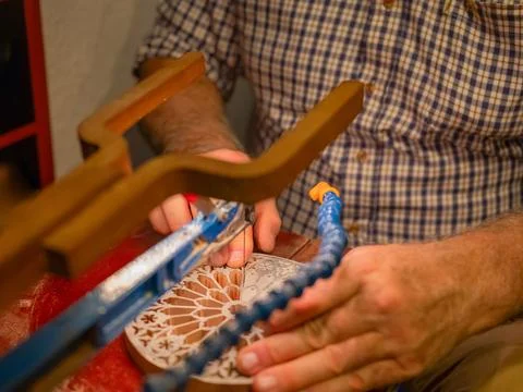 Hands of a craftsman cut out a pattern from wood with a jigsaw Stock Photos