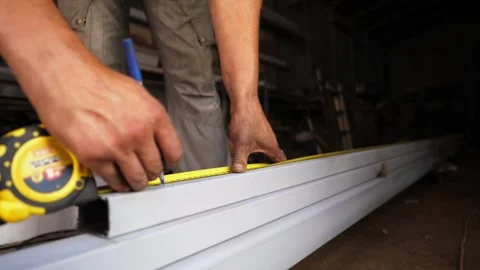 Hands of craftsman measuring iron construction with roulette meter at garage Stock Footage 296366308