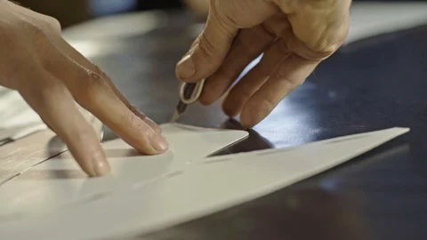 Hands of craftsman placing a pattern on the piece of black leather Stock Footage 123413847