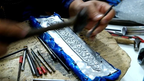 Hands of craftsman using tool carving Thai pattern on metal plate Stock Footage 124452054