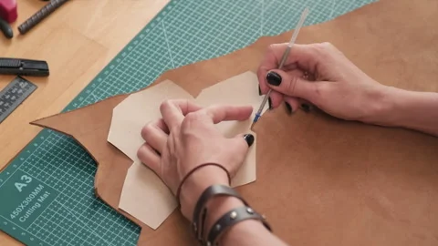 Hands of Craftswoman Putting Stencil on Piece of Leather to Cut Out Stock Footage 246694635