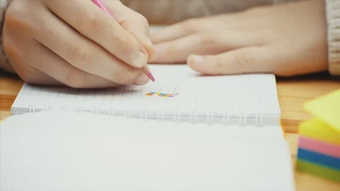 Hands of creative kid who is drawing with pink pencil in her notebook. Stock Footage 113070852