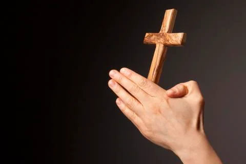 Hands with cross on dark background Stock Photos