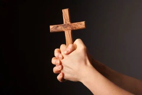 Hands with cross on dark background Stock Photos