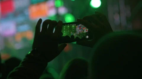 Hands in the crowd holding smart phone and shooting musical performance. Bright Stockbeeldmateriaal 87846235