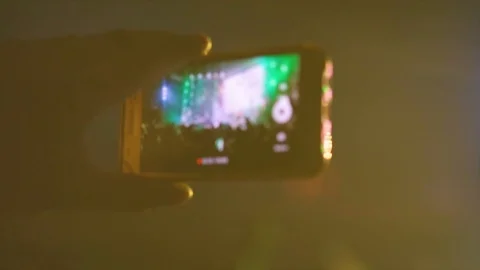 Hands in the crowd holding smart phone and shooting musical performance. Bright Stockbeeldmateriaal 87846394