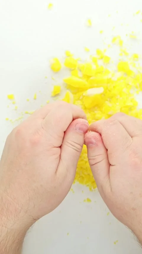 Hands crumbling yellow soap flakes for satisfying ASMR texture Stock Footage 336263196