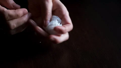Hands crumpling clean paper napkin close-up on black background. Macro shooting Stock Footage 321861917