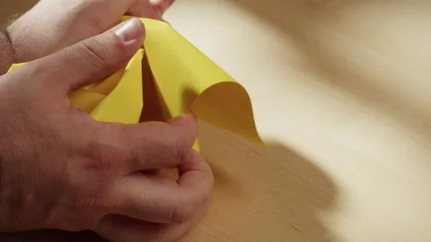 Hands crumpling yellow paper close-up. Macro shooting of crumpled sheet. Video stock 169237812