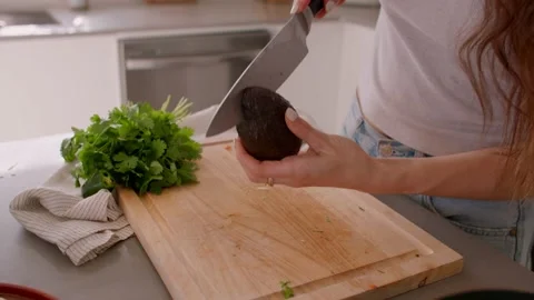 Hands cut avocado on cutting board in kitchen, chop, cooking food 库存影片 220754113