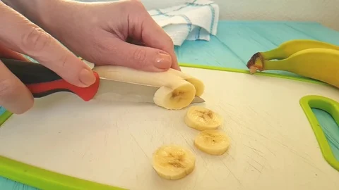 Hands cut a banana in the kitchen Stock Footage 89712875
