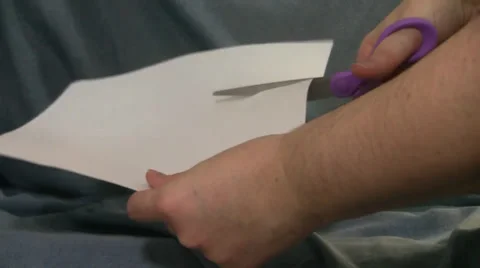 Hands cut blank paper in half with purple scissors blue background Video stock 35533274