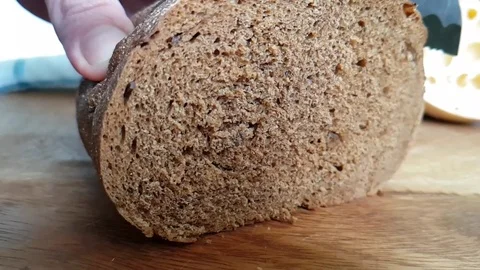 Hands cut bread with a knife on a wooden Video stock 88292918