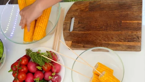 Hands cut corn cobs into pieces Stock Footage 84300636
