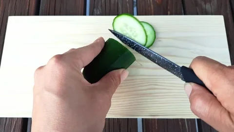 Hands cut cucumber into thin slices. Closeup. Stock Footage 256574548