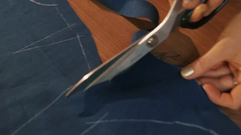 Hands cut the fabric with tailor's scissors, cutting a piece of fabric the Video stock 152098062
