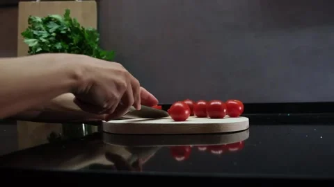 Hands cut fresh cherry tomatoes on a dark background Stock Footage 242906952