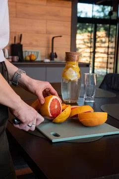 Hands cut grapefruit with a knife for lemonade Stock Photos
