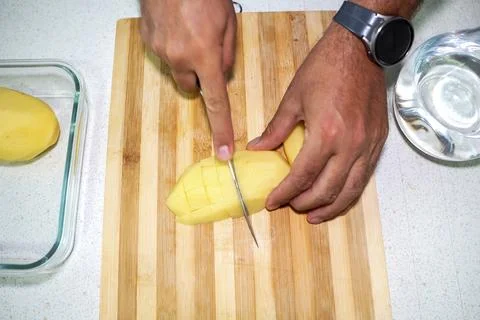 Hands cut mango. Preparing bright yellow mango pieces on clean kitchen surface Stock Photos