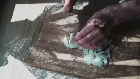 Hands cut the onion with knife. There is a beautiful shadow from the curtain on Stock Footage 133799587