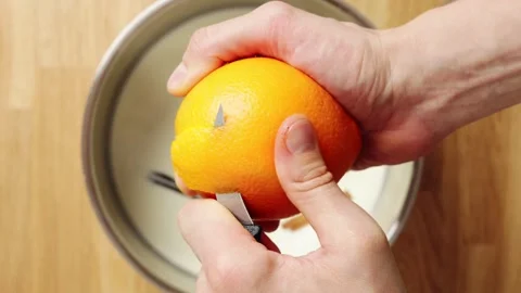 Hands cut orange peel with knife and add it to milk mixture. Stock Footage 345273411